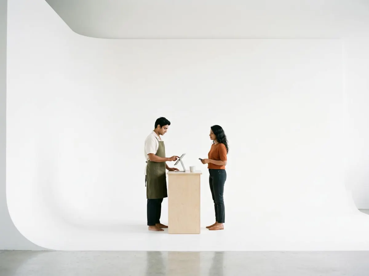 A barista taking an order on a tablet at a small wooden counter