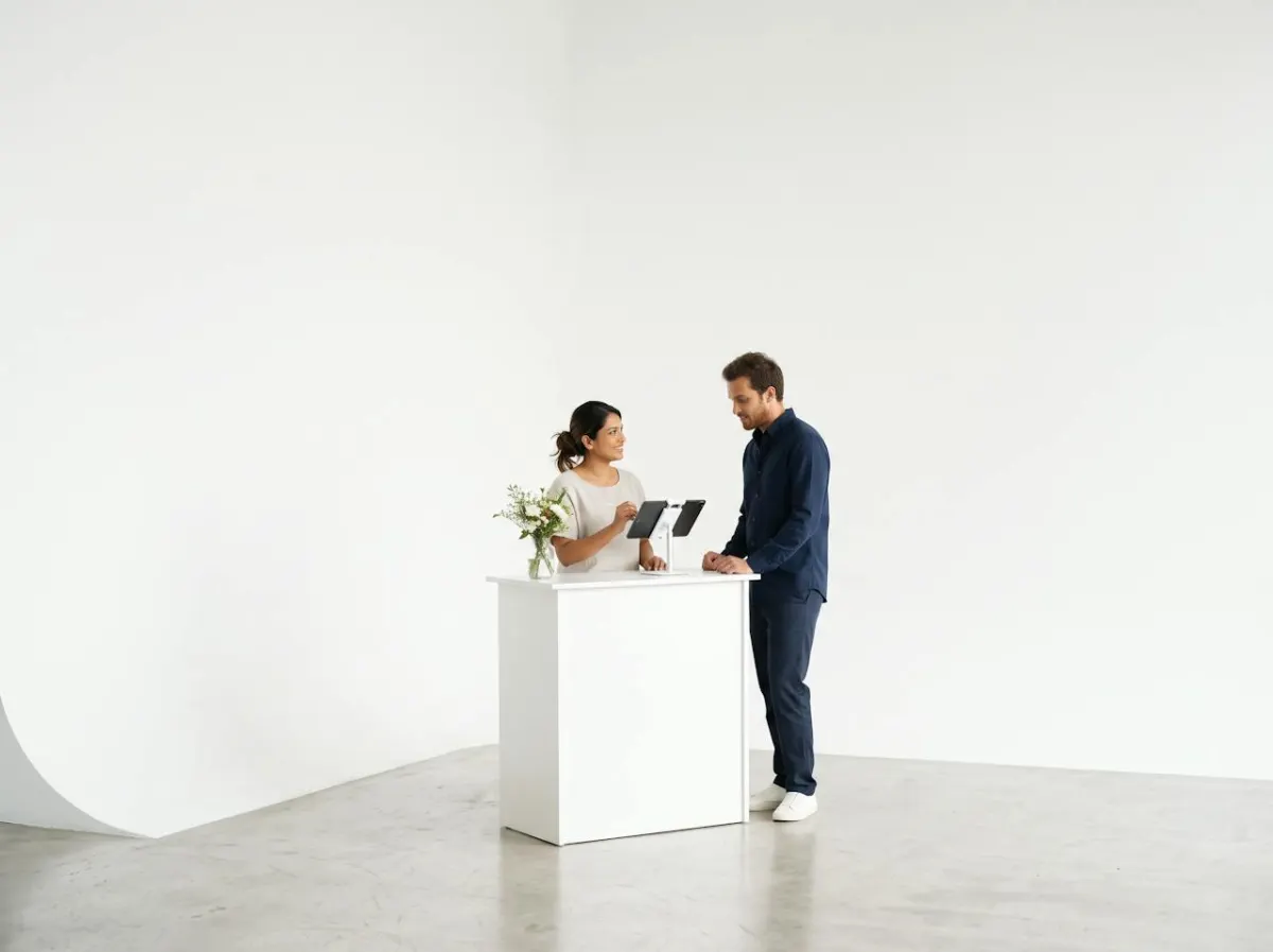 A salon receptionist taking a booking on a tablet at a small front desk